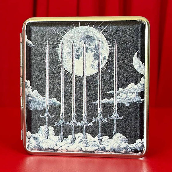 Cigarette case with six of swords tarot card celestial black and white design featuring a moon and six swords against clouds. Shown closed on a red velvet background