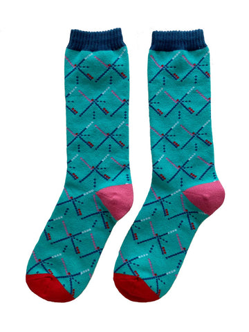 Pair of unisex crew socks with a knit-in pattern of the geometric carpet design of the Portland International Airport. With a teal background, navy blue cuffs, pink heels, and red toes. Shown flat