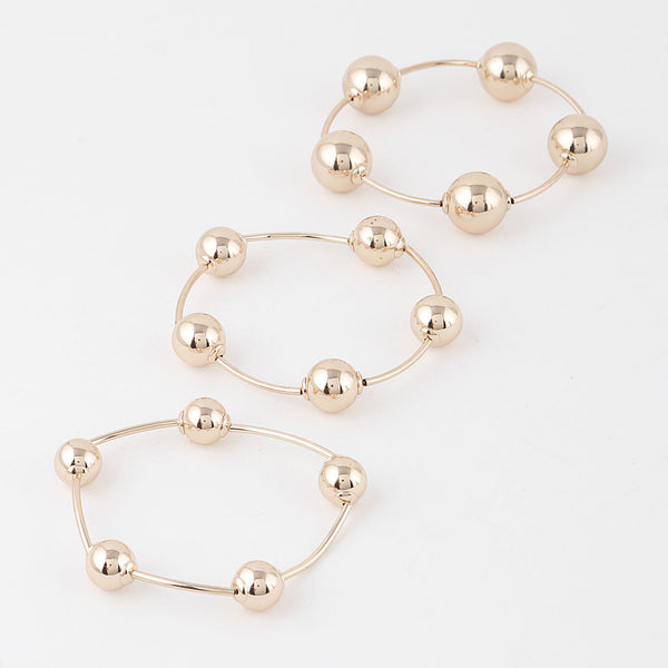Set of three differently sized plastic metallic gold stretch bracelets with round beads in between long segments. Shown flat separately 