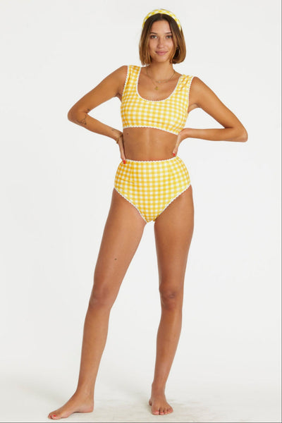 model wearing yellow and white gingham print reversible bikini. Top has scoop neckline and white rickrack style trim. Shown from front with gingham side worn