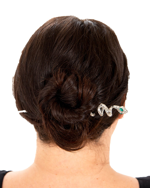 Silver coiled snake-shaped hair pin with large almond-shaped green jeweled eyes shown in updo of model from behind
