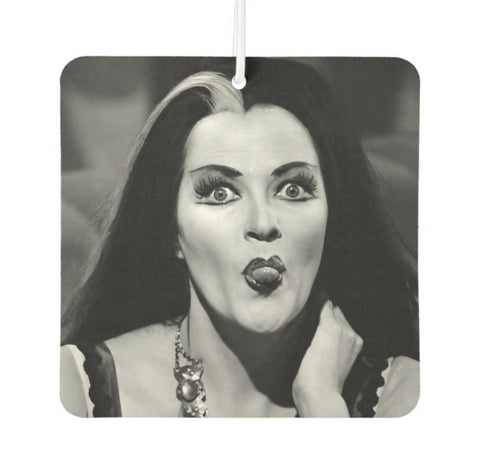 Square air freshener with black and white photograph of Lily Munster sticking out her tongue