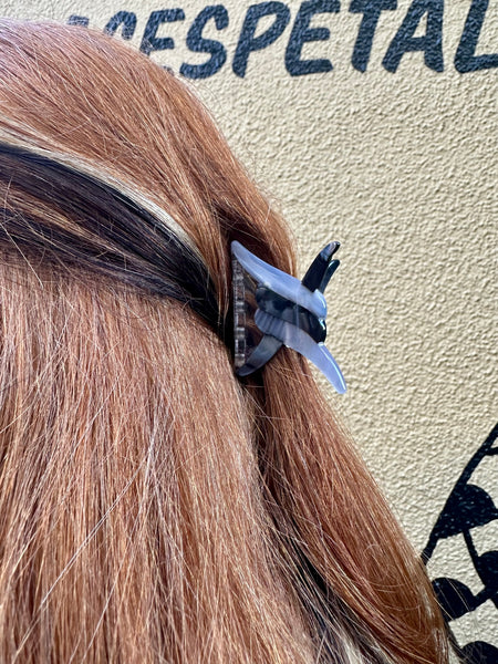 Black and grey marbled acetate hair clip in the shape of a link of barbed wire shown in brown hair in a half up hairdo