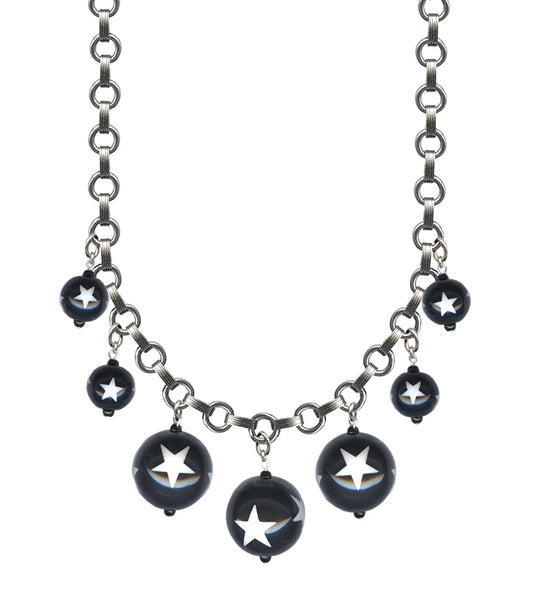 link necklace with 7 varying sizes of round black beads decorated with white stars shown in close up on a white background 