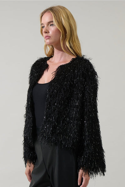 model wearing black shaggy faux fur cropped jacket with metallic fringe throughout. Jacket is collarless. Shown from side