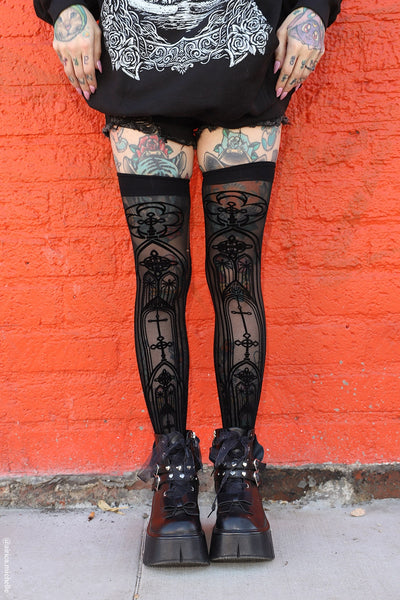 model wearing sheer stay up thigh highs with all over flocked pattern of cathedral arches. Shown from front