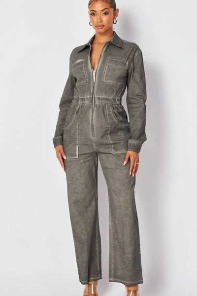 model wearing denim boilersuit in grey mineral wash finish. Boilersuit has long sleeves, pointed collar, silver metal zip down the center, elasticized waist with belt loops, large hip pockets and chest pockets, and full length legs. Shown from front