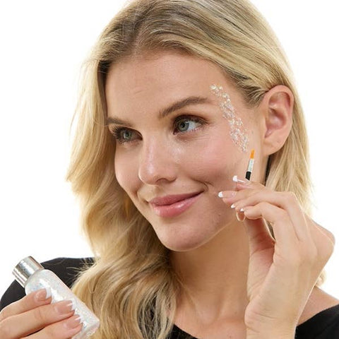 woman applying iridescent white glitter makeup to face with applicator