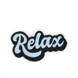 Felt patch with “Relax” written in groovy cursive light blue font with black shadows