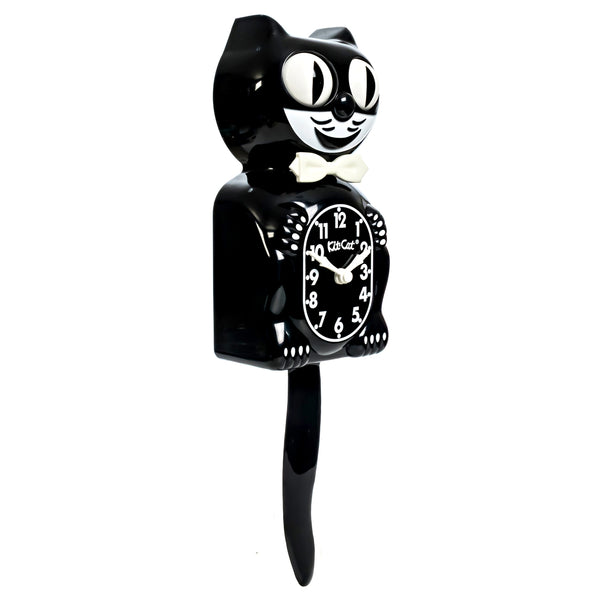black & white glow in the dark Kit-Cat wall mount clock features a mischievous grin, and big round eyes that swivel side-to-side in time with its pendulum tail. Shown in normal lighting from three quarter angle
