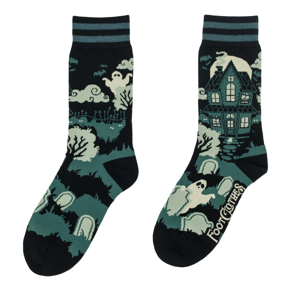 Pair of cotton blend socks in black with teal and black striped cuffs and solid black toes/heels with all-over design of haunted house surrounded by clouds and graveyard with ghosts. Shown flat from opposite side