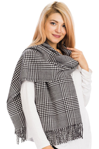 Woman wearing a black and white checkered plaid scarf with fringes on a white background