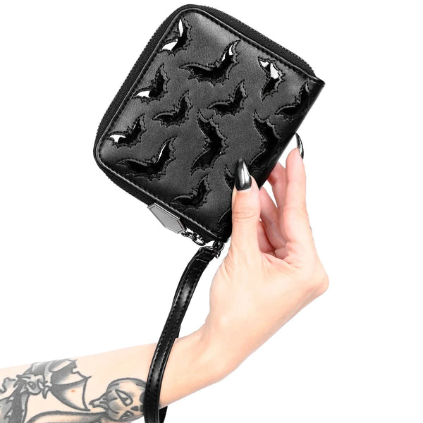 Model holding black faux leather rectangular wristlet wallet with black vinyl bat scattered pattern and matching wrist strap. Shown closed
