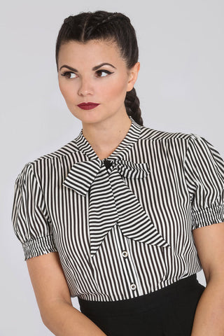 A model wearing a black and white vertical striped slightly puffed short sleeve blouse with a high tie-neck blouse. The sleeves have elasticized shirred cuffs. Shown from the front