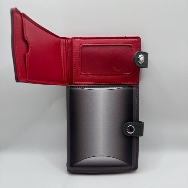 black faux leather wallet in the shape of a casket with two separate silver metal snap closures to replicate the headpanel and footpanel. Shown with top compartment open from front to display red interior