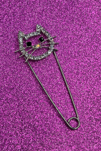 silver metal safety pin with pin closure in the shape of a cat head with clear "rhinestone" jewels & black jewels for eyes