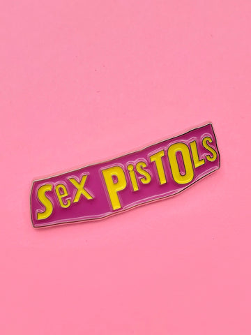 newspaper collage style logo for the Sex Pistols (designed by Jamie Reid) in bright yellow and purple enamel on a silver metal clutch-back pin.

