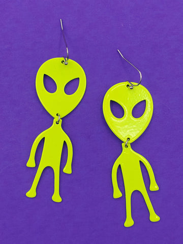 pair of neon yellow acrylic laser cut dangle earrings in the shape of aliens with large heads, eyes, and skinny arms and legs 