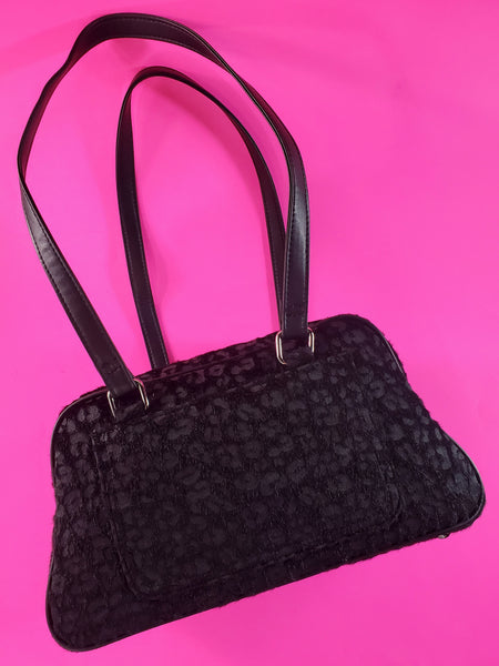 Trapezoid-shaped purse in a black on black leopard pattern printed on fuzzy faux pony with matching matte faux leather trim and shoulder straps, showing the back view with exterior open pocket