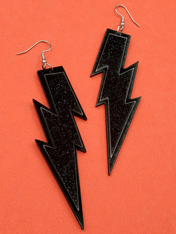 pair of sparkly black  glitter and shiny black layered laser-cut acrylic lightning bolt dangle earrings, shown flatlay