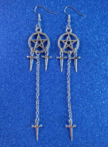 pair of pentagram dangle earrings in shiny silver metal with both a pair of 3/4” dagger charms hanging from each pentagram & a 2 1/2” link chain connecting another dagger to the bottom of the earring