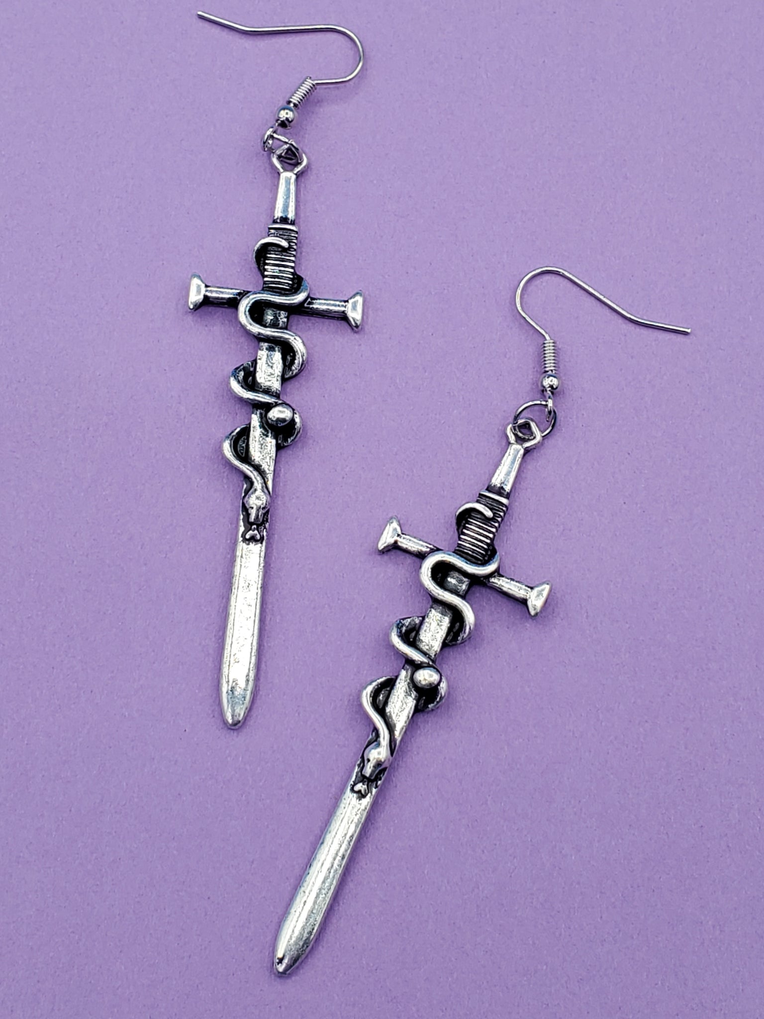 burnished silver metal sword dangle earrings with a snake wrapped around each blade