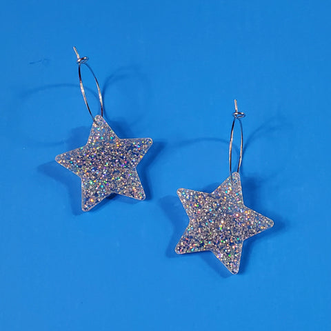 sparkly pair of silver glitter star-shaped acrylic resin charm hanging from a delicate silver plated hoop earrings