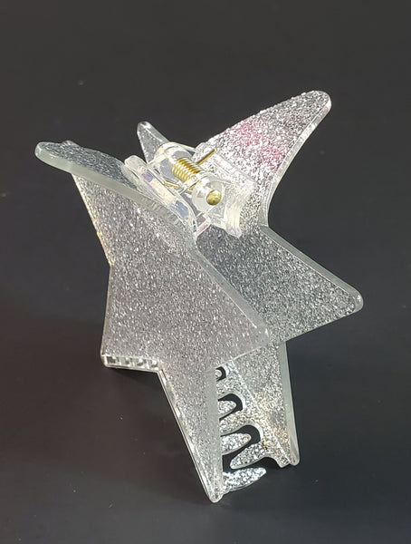 3 1/2” claw style clear acrylic with silver glitter hair clip in the shape of a pointy star. Shown from the side.