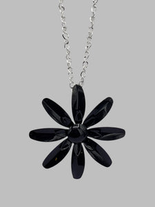 vintage-inspired metal daisy pendant in classic black on a 28” long shiny silver metal link chain