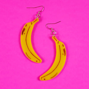 pair of yellow banana shaped laser cut acrylic earrings with etched brown "ripeness" details