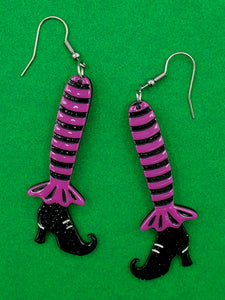 pair of resin dangle earrings in the shape of striped black and purple legs with black glittery pointed toe witchy boots