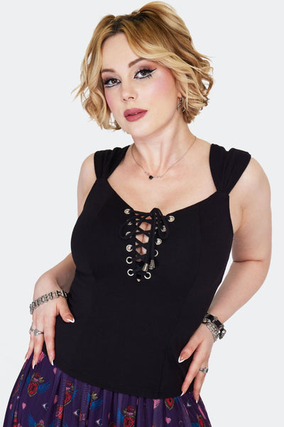 model wearing black stretch knit top open neckline with black cord laced bodice with silver metal grommets, wide gathered straps, princess seaming, Shown untucked into skirt from front