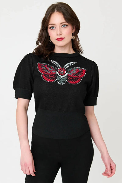 Model wearing black knit pullover sweater with round neckline, slightly puffed balloon short sleeves, wide ribbed bottom band, and jacquard knit image across bust of a stylized moth in black, white, grey, and teal. Shown from front