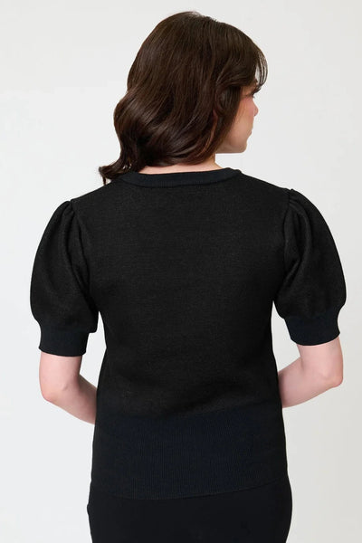 Model wearing black knit pullover sweater with round neckline, slightly puffed balloon short sleeves, wide ribbed bottom band, and jacquard knit image across bust of a stylized moth in black, white, grey, and teal. Shown from back