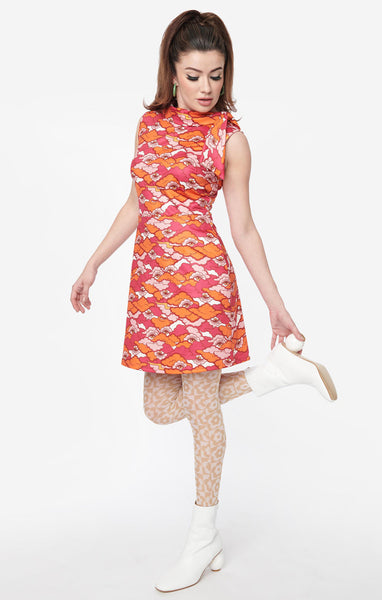 60s style fit & flare sleeveless mini dress iin an illustrated pattern of eyes gazing at you from a creamy sky filled with pink and orange clouds, shown on a model