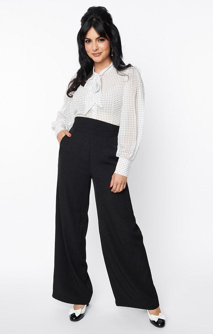 Model wearing high waisted black trousers with a wide cummerbund style waist and wide legs. Shown from front