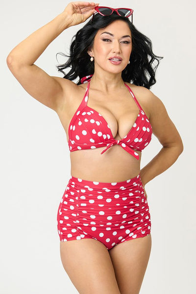Red and white polka dot patterned halter style bikini top with front bow detail, shown on model from front