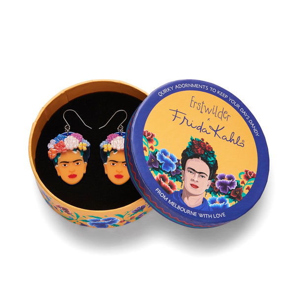 pair Frida Kahlo Collection “My Own Muse Frida” layered resin portrait dangle earrings, showing face of Frida with assorted color flowers in her hair, in illustrated round box packaging
