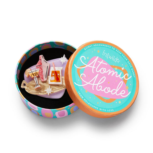 Atomic Abode Collection "Shaken or Stirred" mid-century style tray holding cocktail, shaker, and pitcher against lavender plaque shape background layered resin brooch, shown in illustrated round box packaging