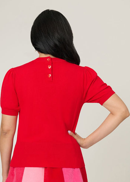 back view of bright red short sleeve sweater featuring heart-shaped button closure at nape. shown on a model