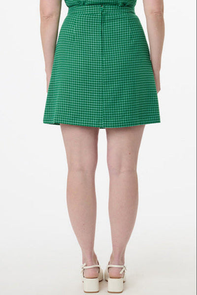 model wearing woven a-line mini skirt in bright green and white houndstooth print with patch pockets. Shown from back