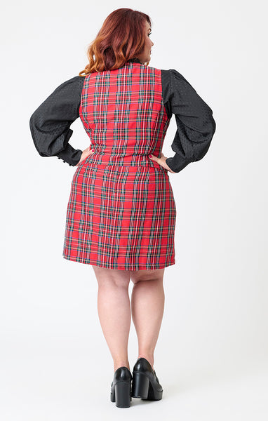 plus size model wearing an a-line red plaid mini skirt with patch pockets on a white background. Shown from back