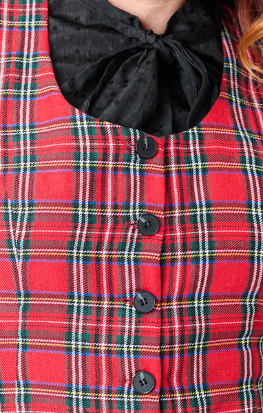 red plaid vest with vertical seaming, a round neckline, and black button closure. Shown layered with black blouse from front in close up