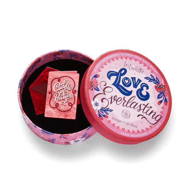 Love Everlasting Shea O'Connor collaboration collection "Cuddle Up Partner" layered resin pink valentine card with "Cuddle Up, Partner" text and red envelope brooch, shown in illustrated round box packaging