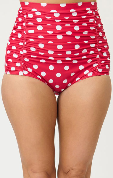 Bright red and polka dot patterned 50s style high-waist ruched front swim bottoms, shown on model from front in close up
