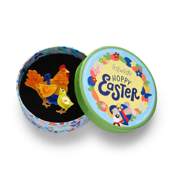 Hoppy Easter Collection “Mother Hen Knows Best” light brown hen in blue apron standing next to yellow chick layered resin brooch, shown in illustrated round box packaging