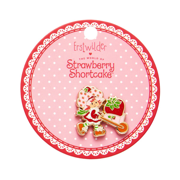 "Strawberry Wheelbarrow" Strawberry Shortcake character pushing strawberry in a wheelbarrow enameled gold metal clutch back pin, shown on illustrated round box packaging