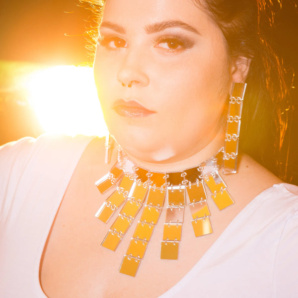 A choker necklace made of Laser-cut square pieces of mirrored silver acrylic hand linked and attached to a chain. Shown on a model 