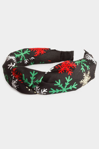 Assorted size red, green, yellow, and white snowflakes print on a knotted black fabric-covered flexible headband