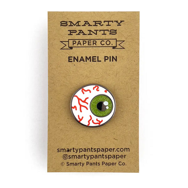 The enamel pin on its cardboard packaging 